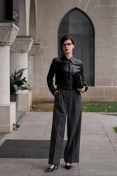 a lady in a black PU leather jacket and a pair of grey pleated pants